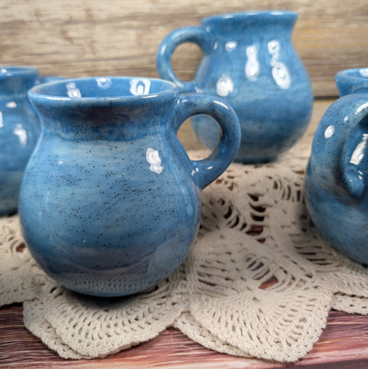 Blue ceramic mugs on a lace doily with a wooden background