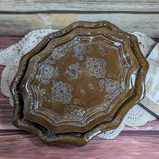 Decorative brown ceramic tray with floral patterns on a wooden surface.