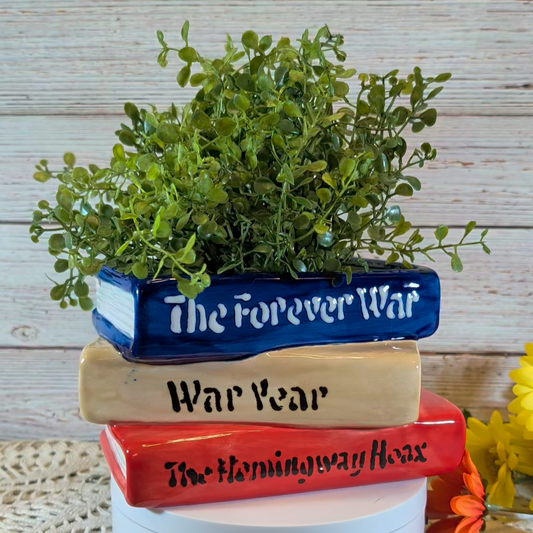 A planter that looks like a stack of books, on a plastic stand, with a wooden background.