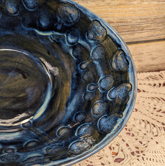 Close-up of a blue ceramic dish with textured design on a wooden surface.