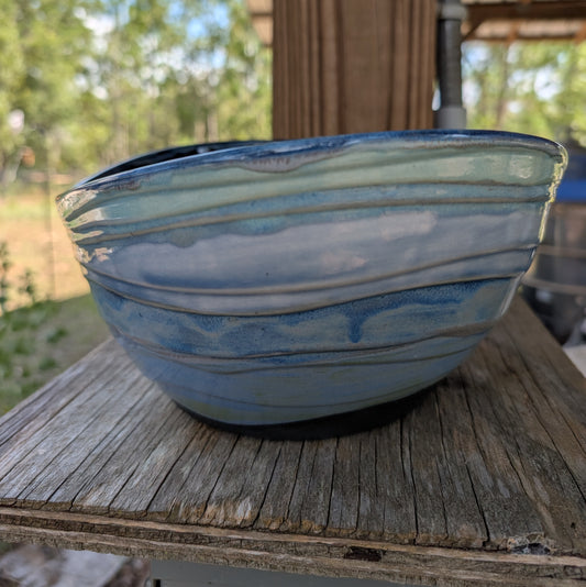 Blue ceramic bowl on a wooden surface with a blurred outdoor background