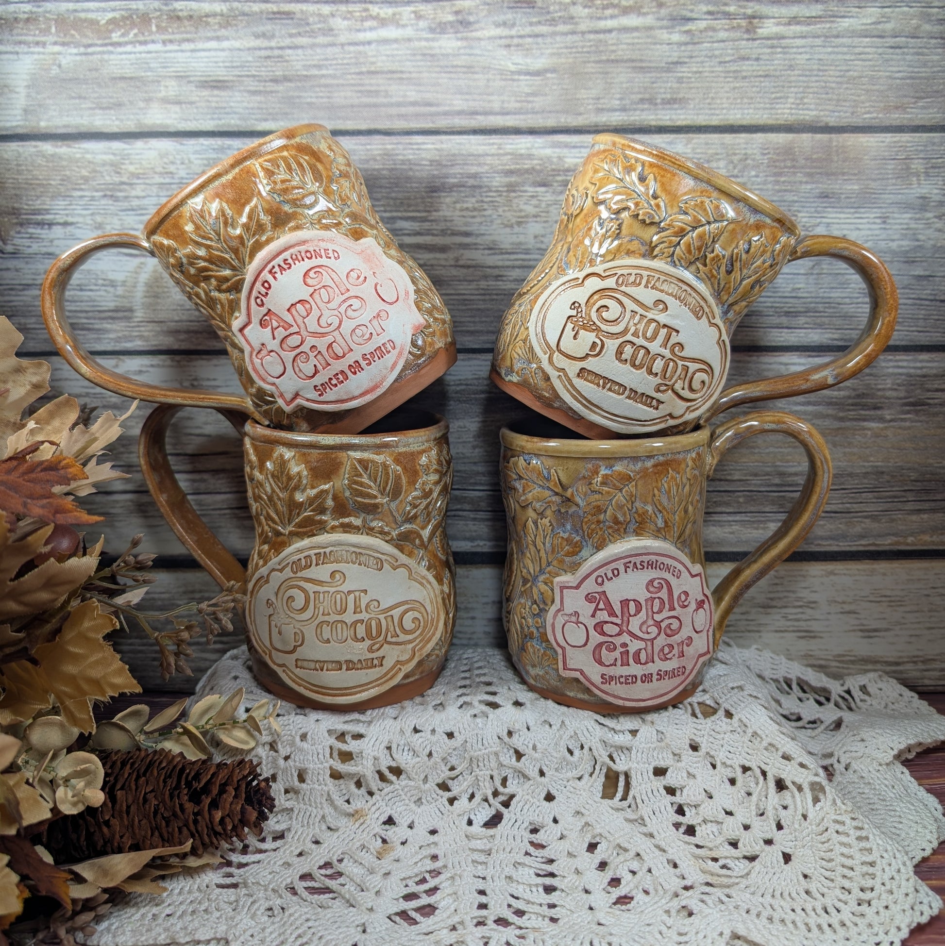 Set of four vintage-style apple cider mugs on a lace tablecloth with a wooden background.