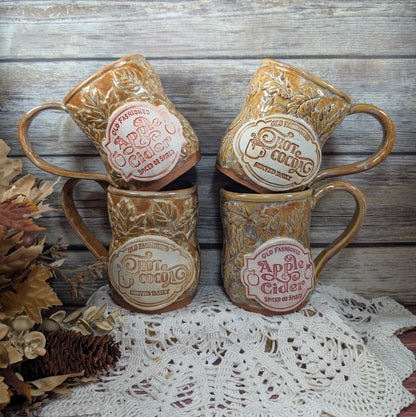 Set of four vintage-style apple cider mugs on a lace tablecloth with a wooden background.