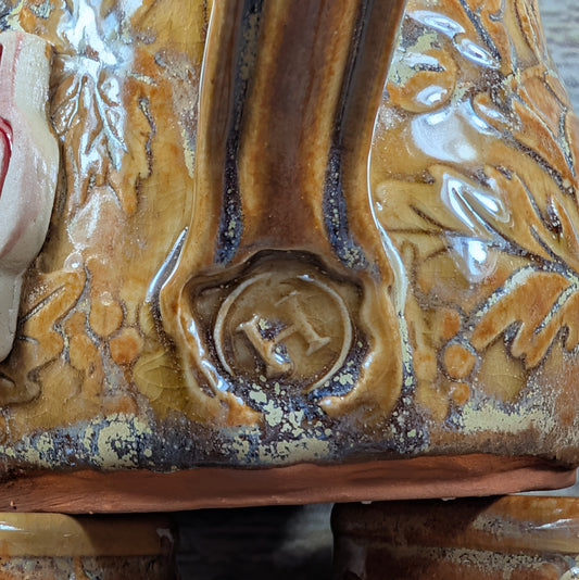 Close-up of a ceramic piece with a logo in the center, featuring brown and beige colors.