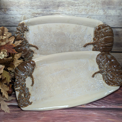Decorative ceramic tray with ornate handles on a wooden surface