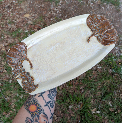 White ceramic tray with brown animal designs on a grassy background