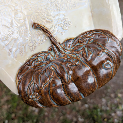 Decorative ceramic piece with embossed design on a textured white surface