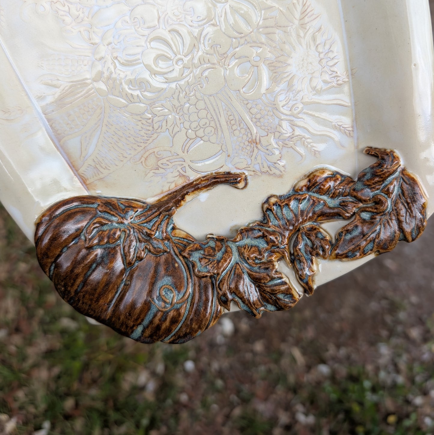Decorative ceramic item with embossed floral design and bronze leaf detailing.