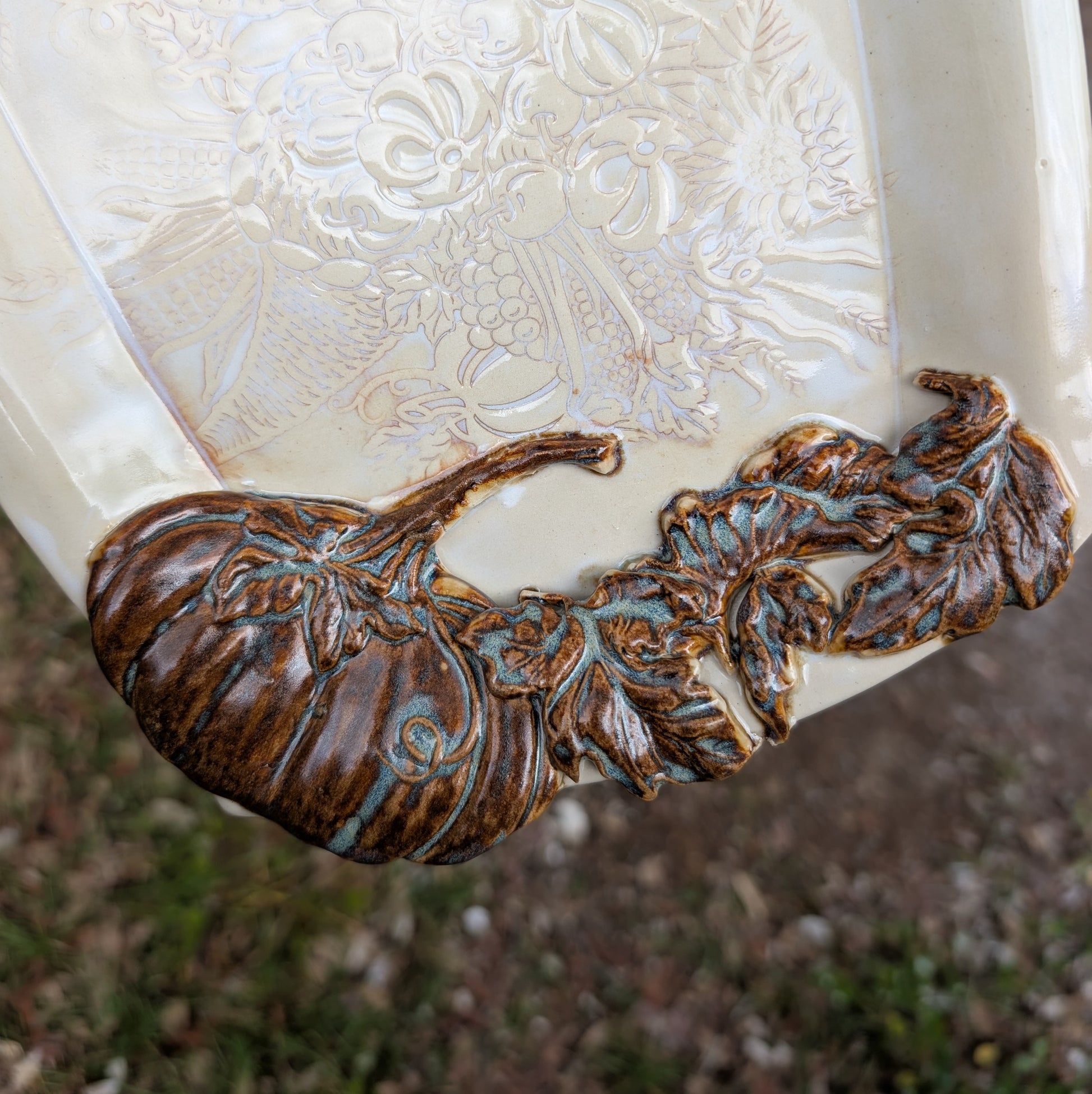 Decorative ceramic item with embossed floral design and bronze leaf detailing.