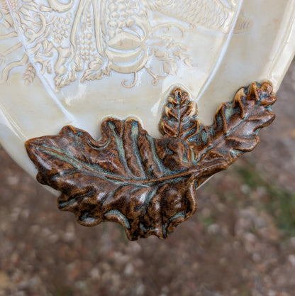Decorative ceramic item with leaf design on a textured surface
