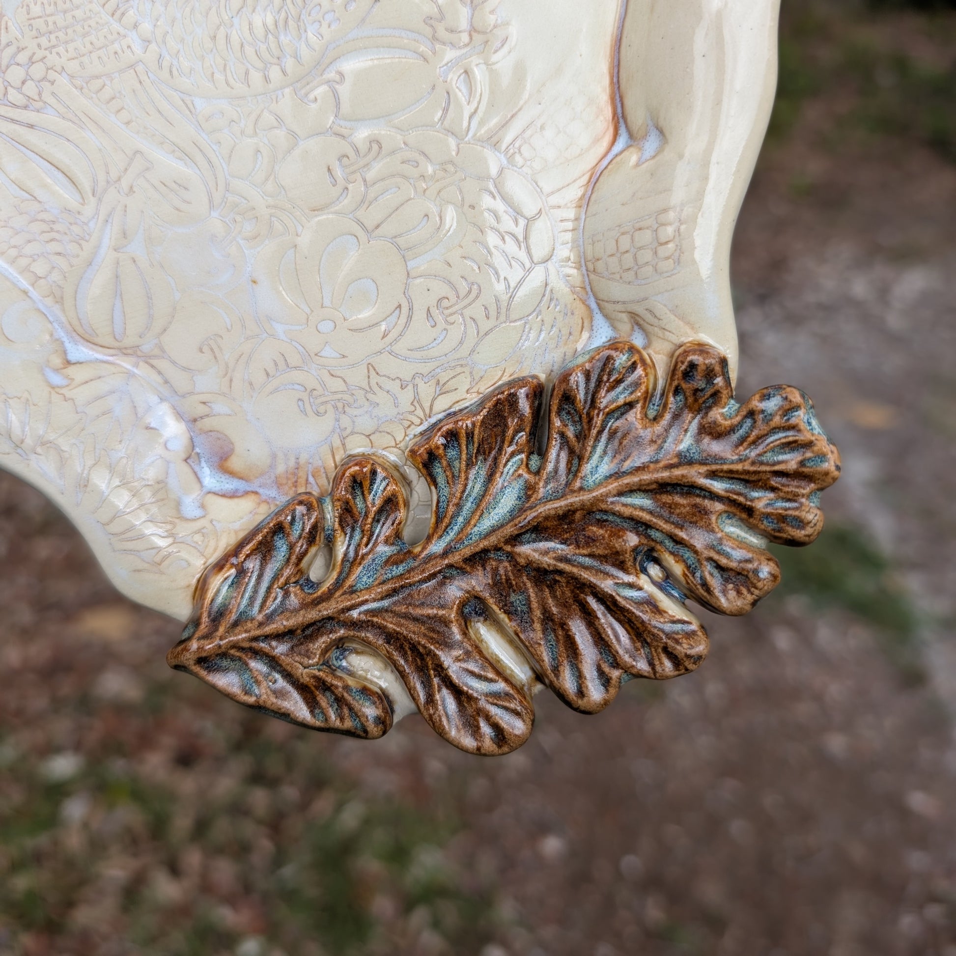 Decorative leaf design on a ceramic piece with a textured surface.