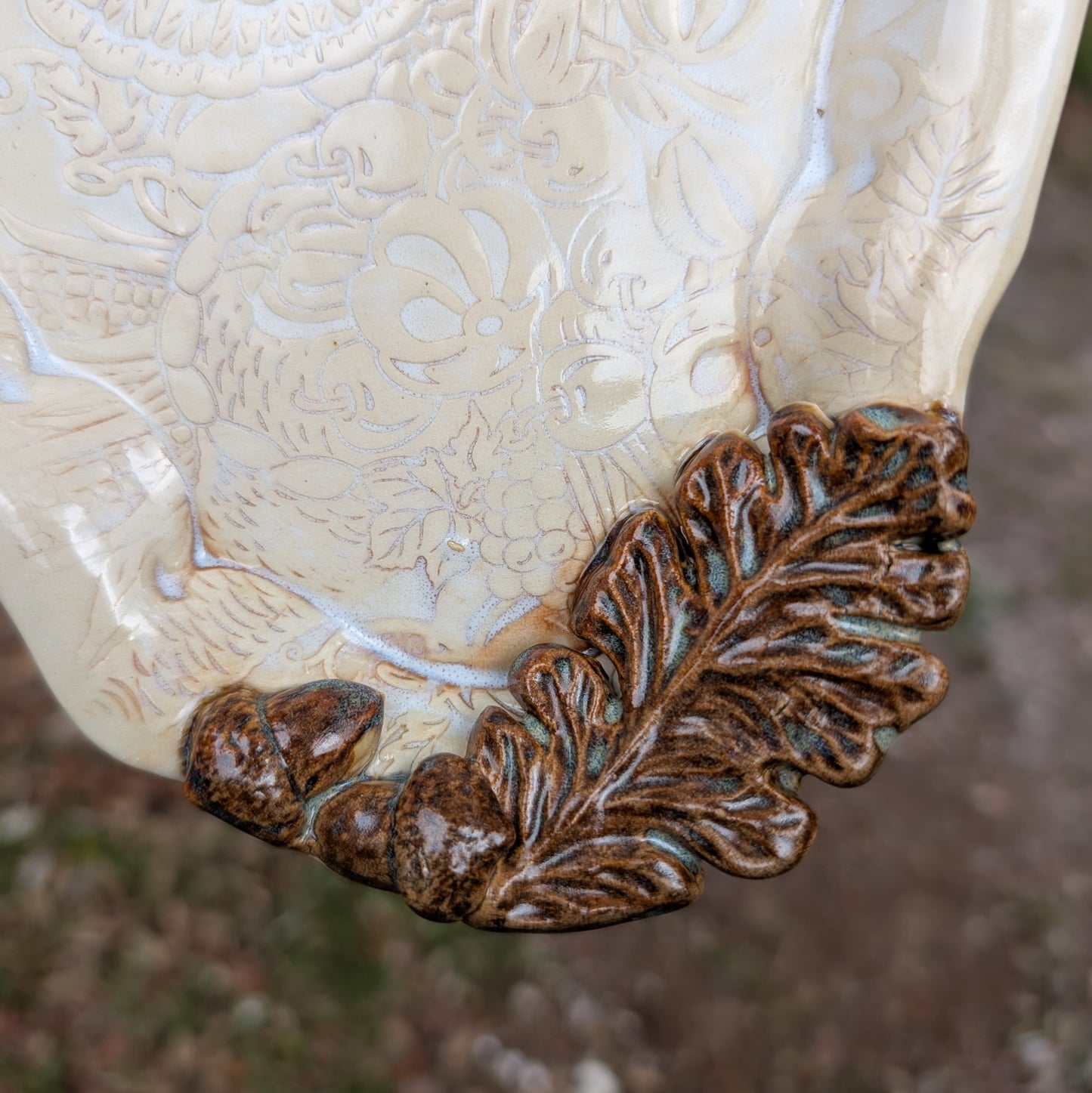 Decorative ceramic piece with a leaf design on a textured surface