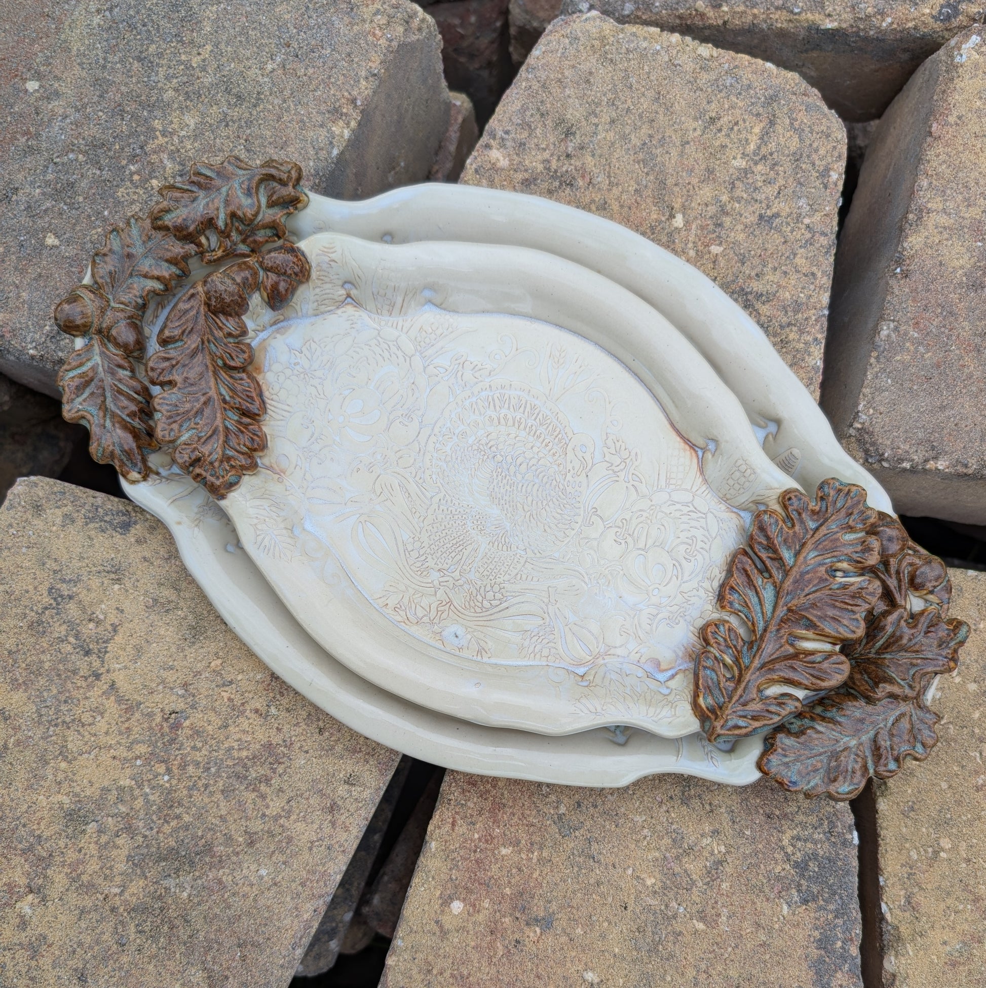 Decorative ceramic dishes with leaf designs on a rocky surface