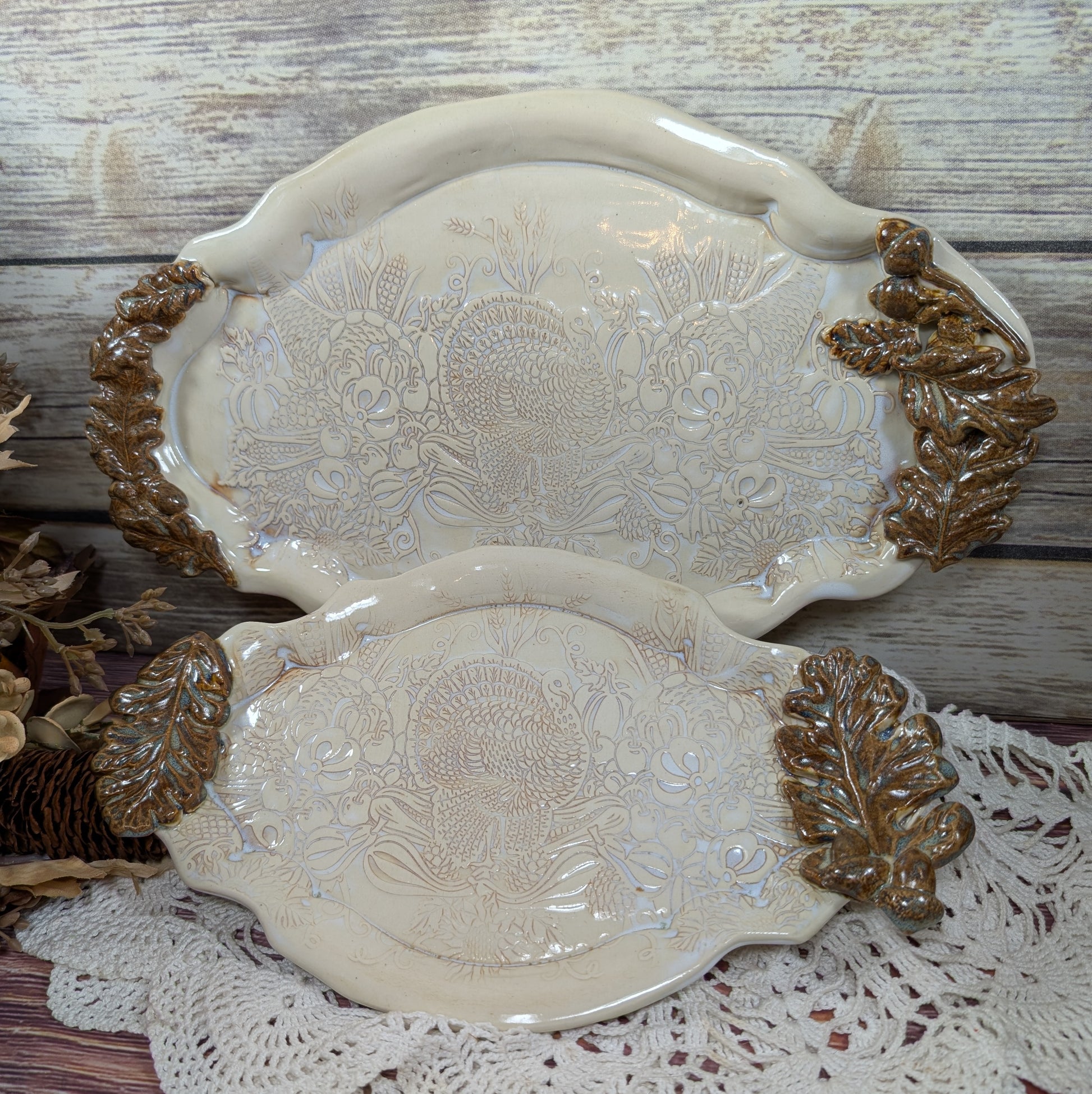 Two ceramic serving trays with embossed designs on a wooden surface.