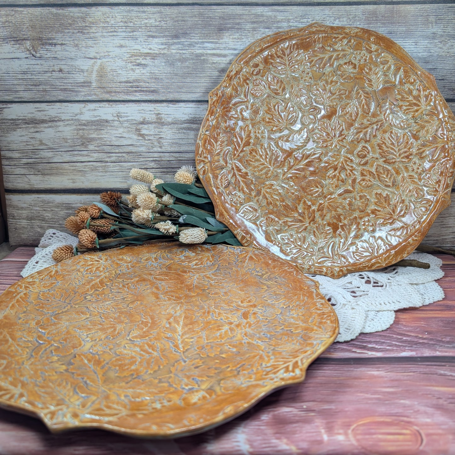 Two decorative ceramic plates with leaf patterns on a wooden surface.