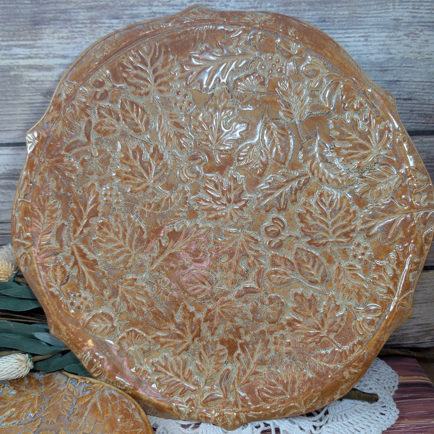 Decorative ceramic plate with leaf pattern on a wooden surface