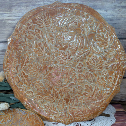 Decorative ceramic plate with leaf pattern on a wooden surface
