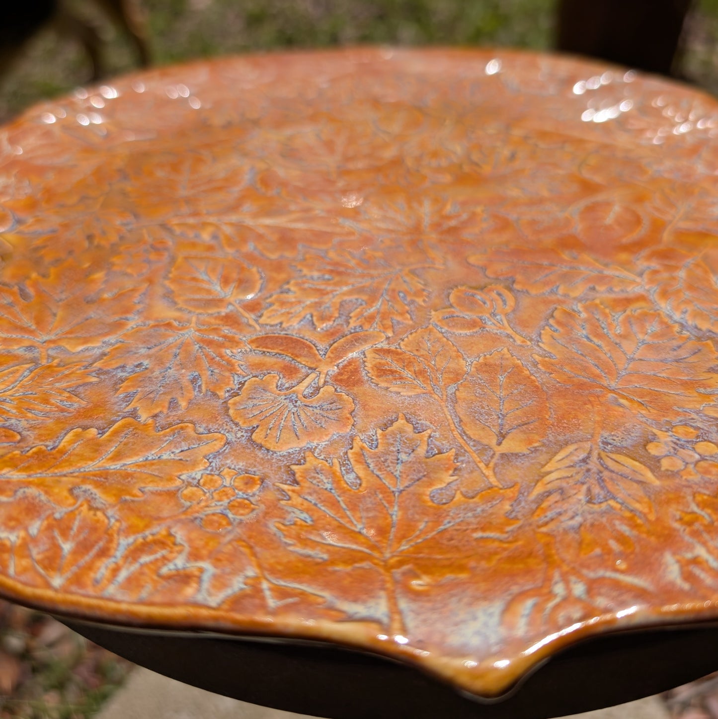 Ceramic plate with leaf embossing on a blurred natural background