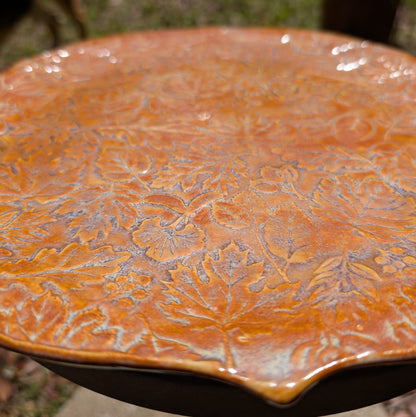 Ceramic plate with leaf embossing on a blurred natural background