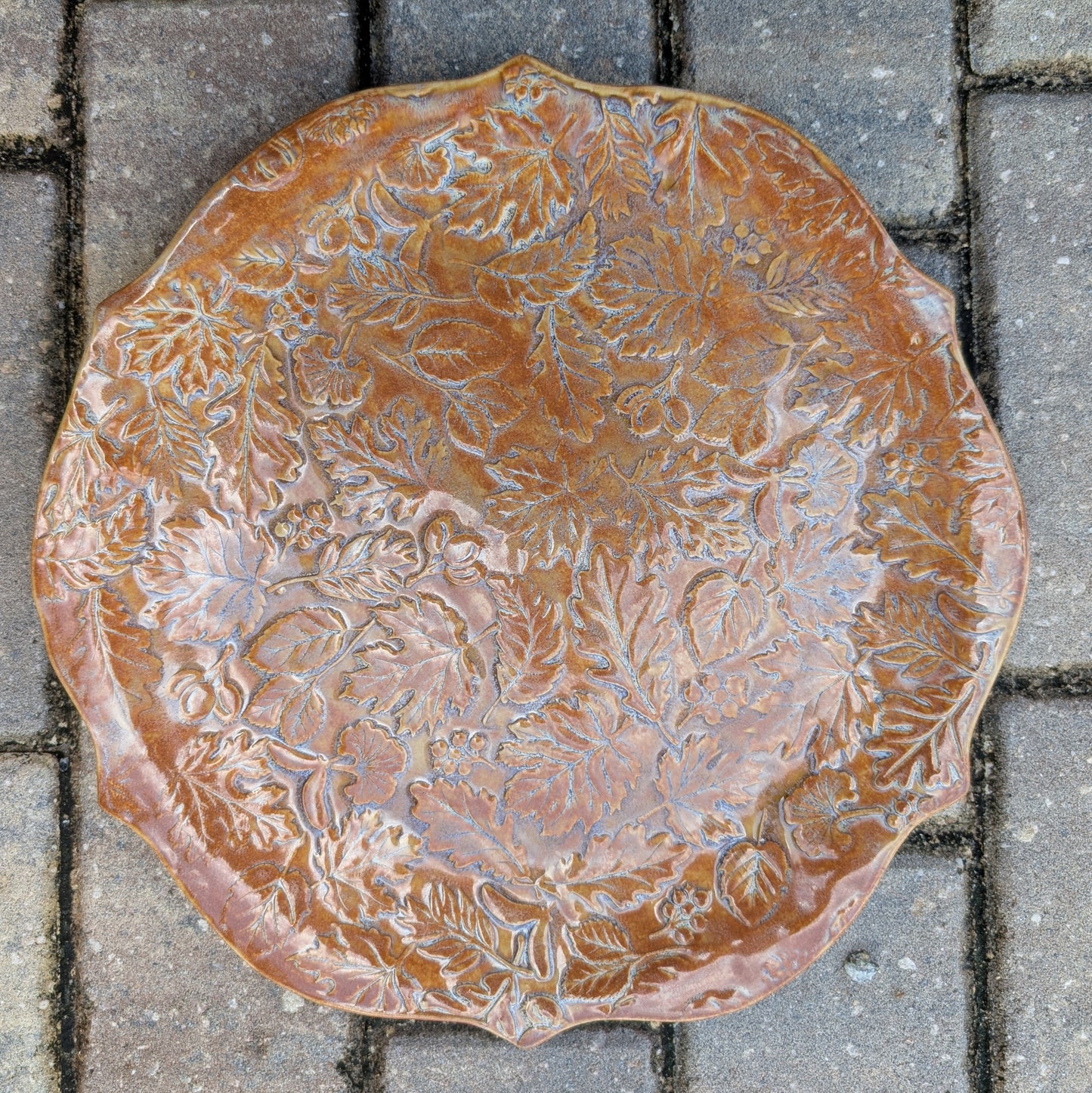 Decorative ceramic plate with leaf patterns on a tiled floor