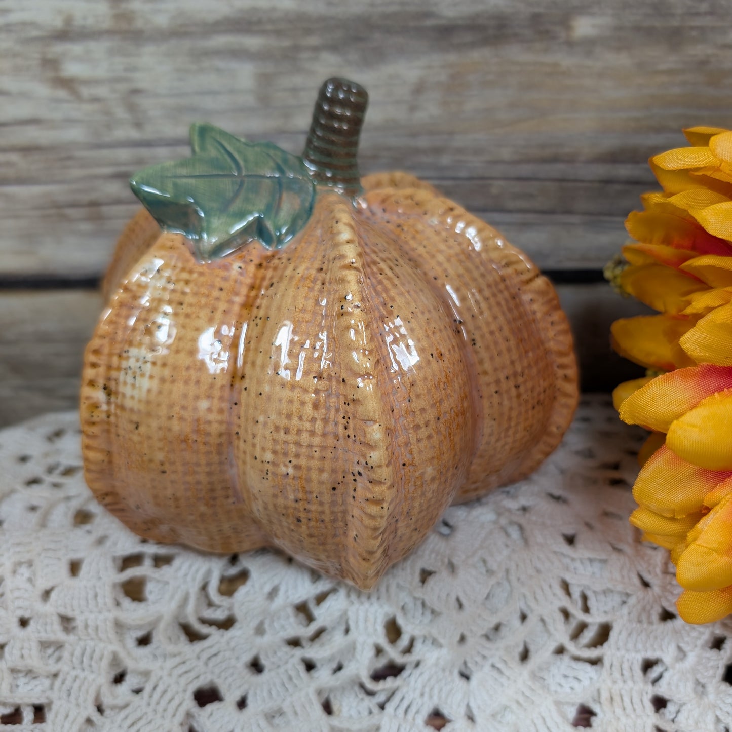 Decorative woven pumpkin on a lace tablecloth with a wooden background