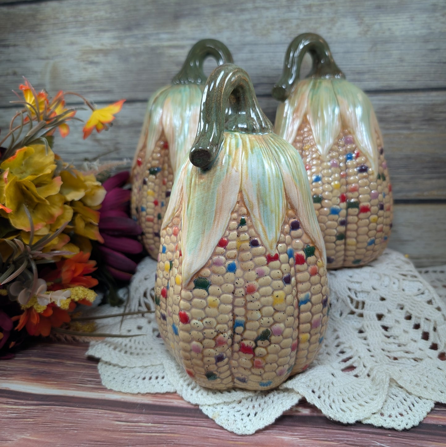 Decorative corn-shaped sculptures with colorful kernels on a wooden surface.