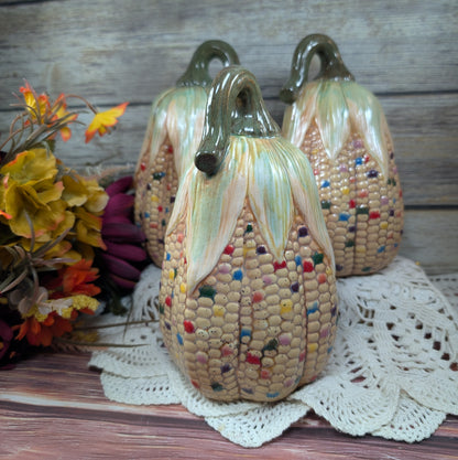 Decorative corn-shaped sculptures with colorful kernels on a wooden surface.