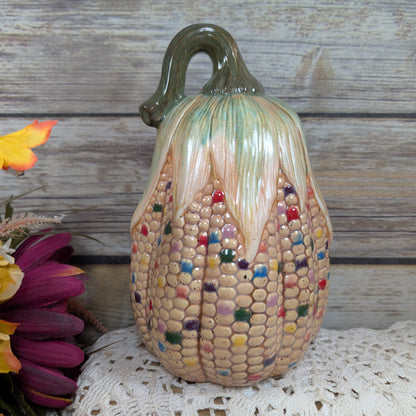 Decorative corn sculpture with multicolored kernels on a wooden surface.