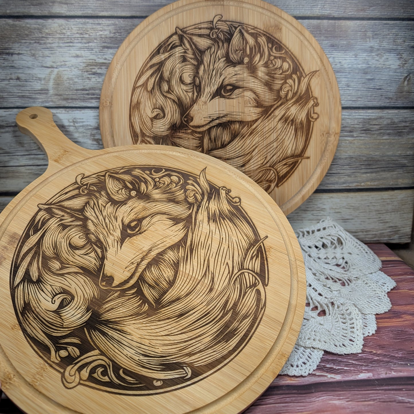 Two wooden cutting boards with engraved fox designs on a rustic wooden surface.