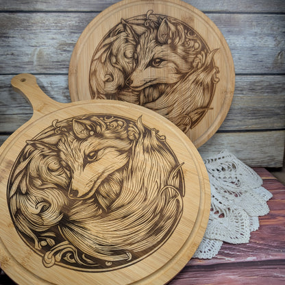 Two wooden cutting boards with engraved fox designs on a rustic wooden surface.