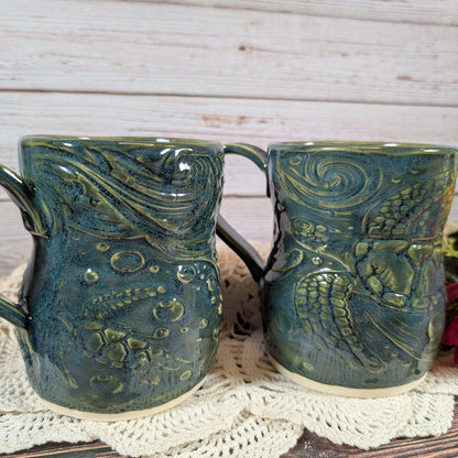 Two green ceramic mugs with textured design on a white doily.