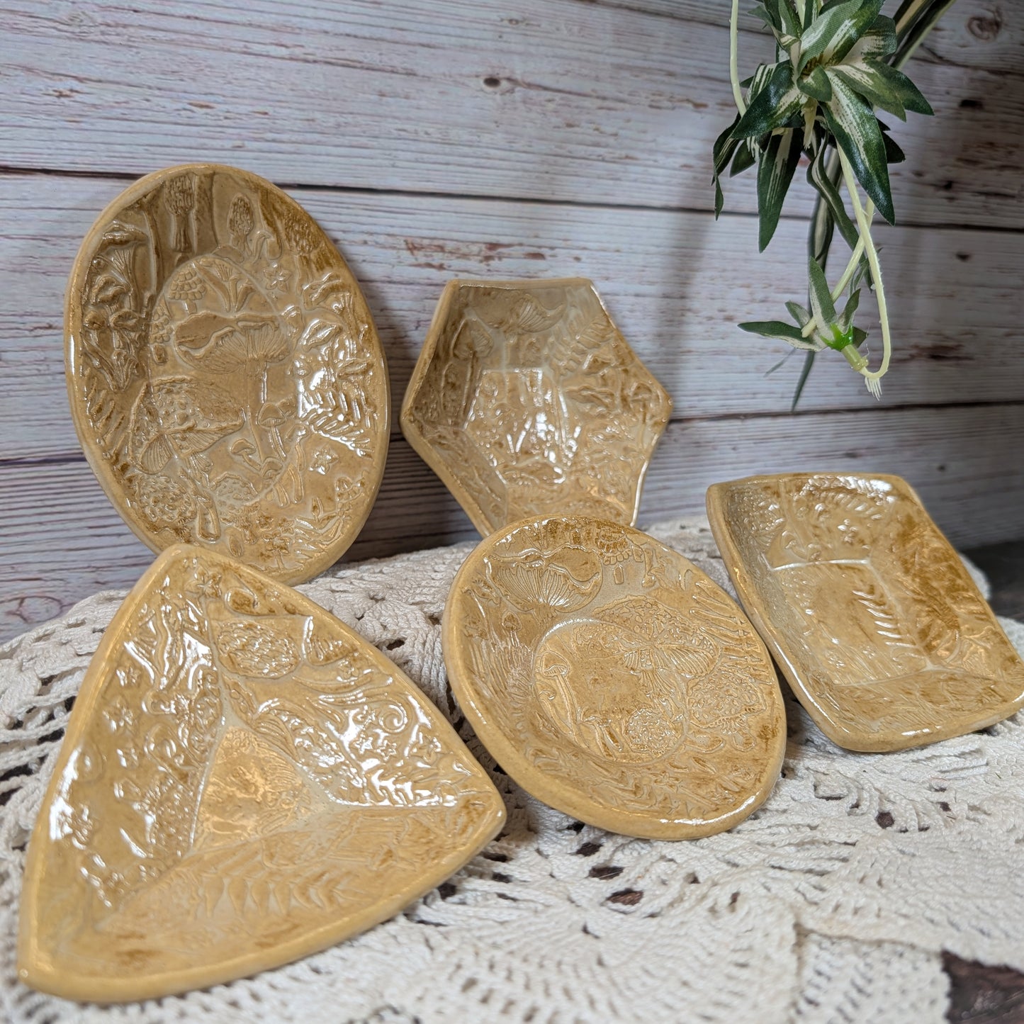 Set of small ceramic trinket dishes, decorated with a mushroom motif, on a lace doily with a wooden background