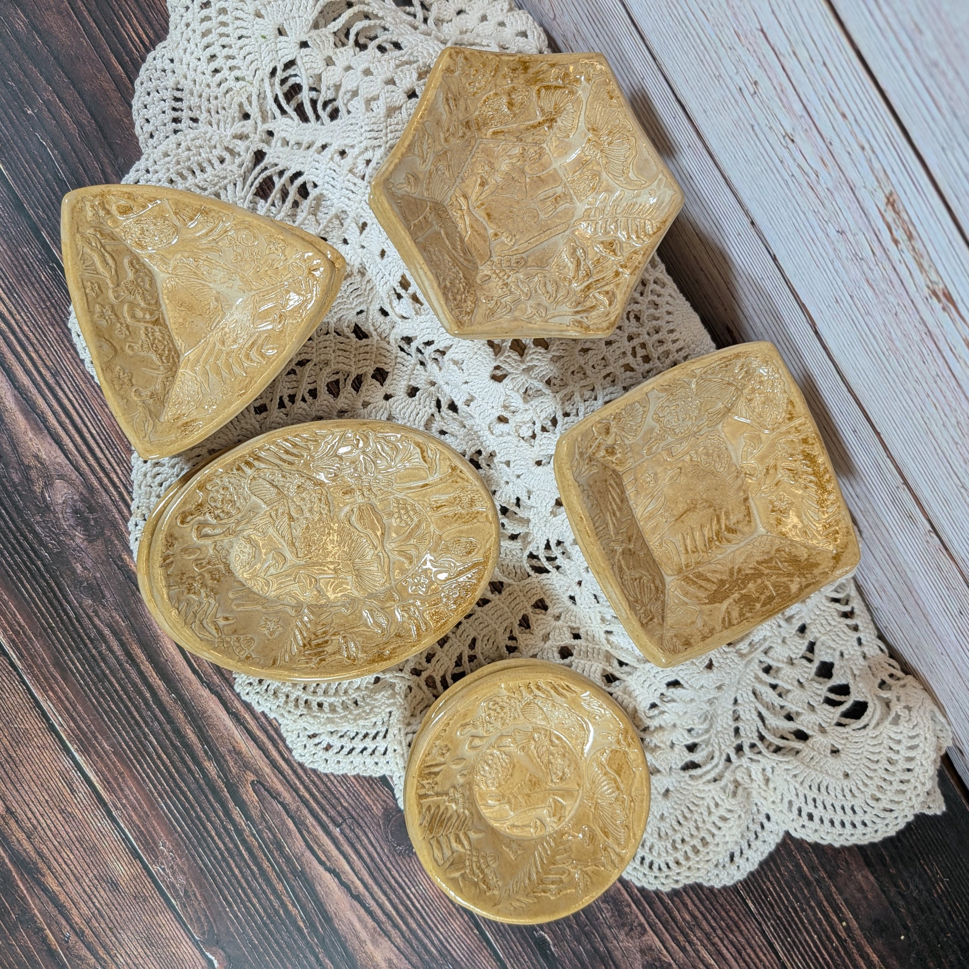 Set of small ceramic trinket dishes, decorated with a mushroom motif, on a lace doily with a wooden background