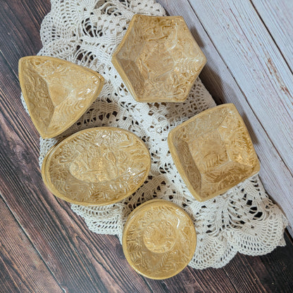 Set of small ceramic trinket dishes, decorated with a mushroom motif, on a lace doily with a wooden background